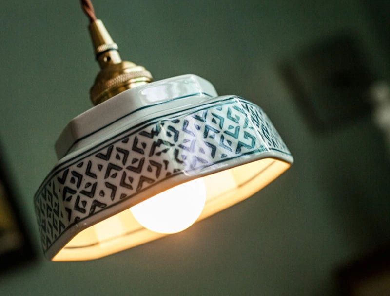 Close-up of white ceramic pendant lamp with intricate blue pattern and LED bulb, perfect for elegant home lighting.