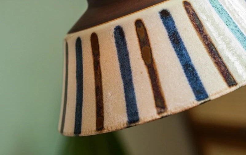 Detail of hand-painted ceramic pendant lamp with vertical blue and brown stripes, ideal for modern lighting decor.