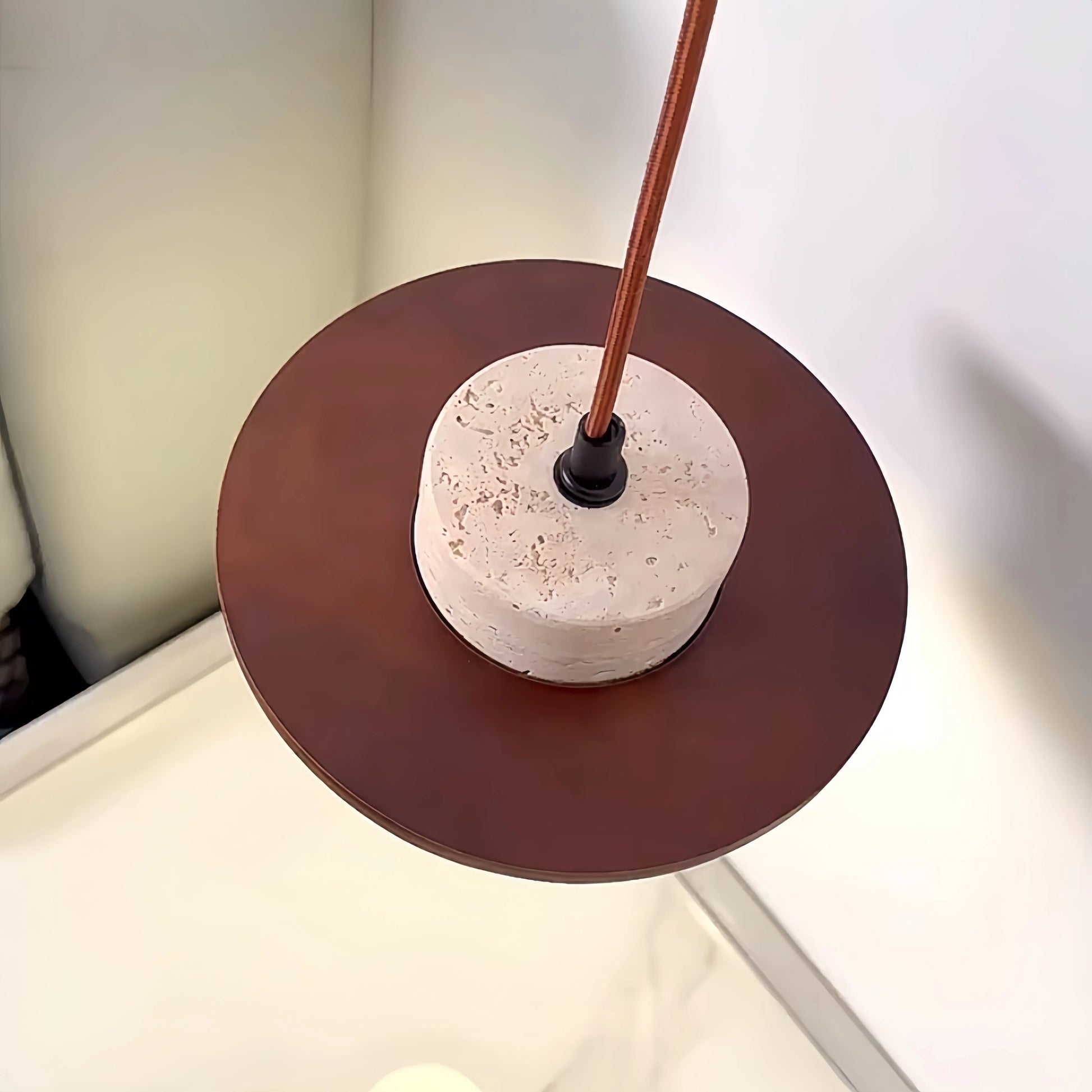 Top view of LUXELY Japanese stone pendant lamp with dark wood disc and travertine body, highlighting minimalist craftsmanship.