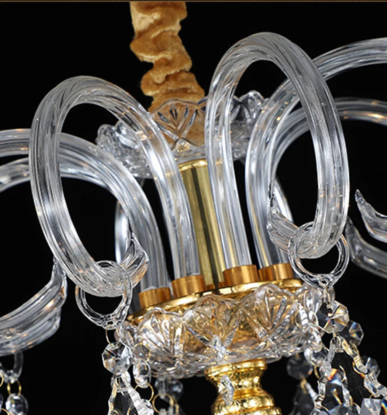 Top detail of golden crystal chandelier showing clear looped glass arms and gold accents for a luxurious finish.