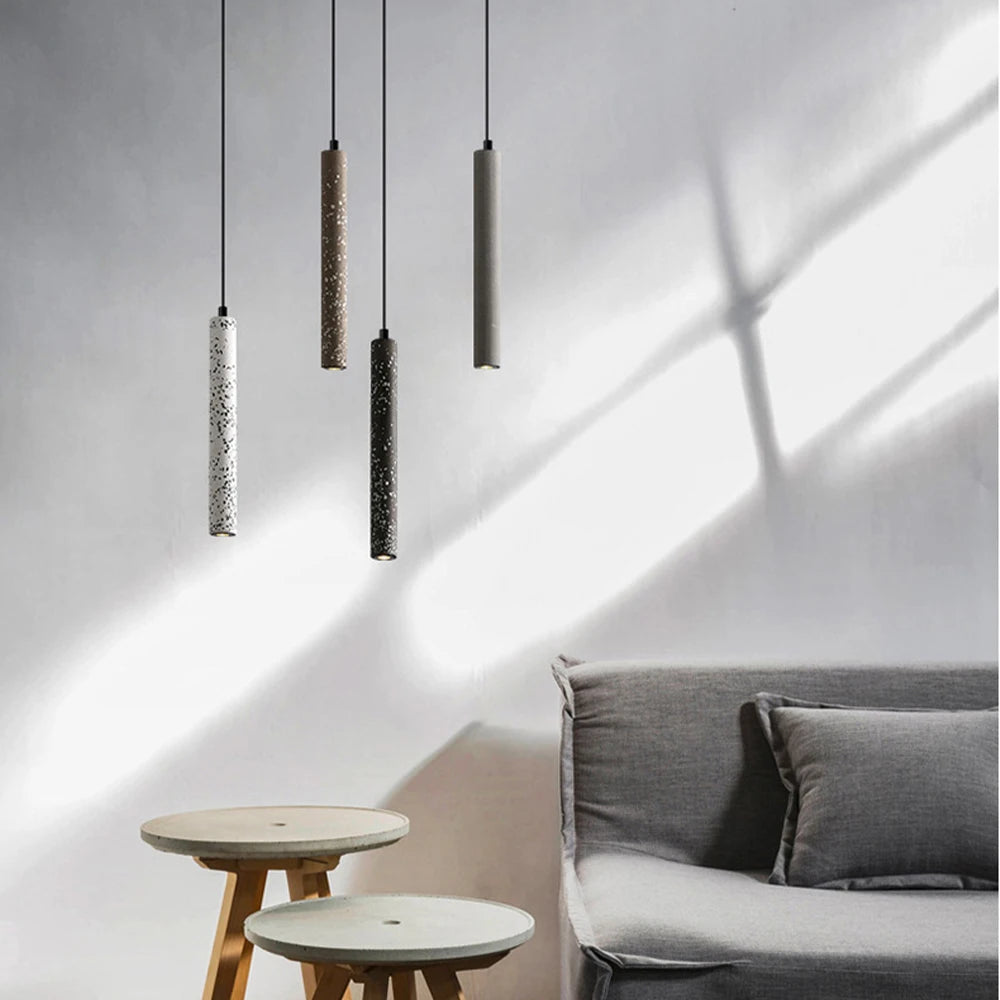 Minimalist LUXELY LED pendant lights in neutral tones above a cozy seating area. Industrial cement design suits modern home decor.