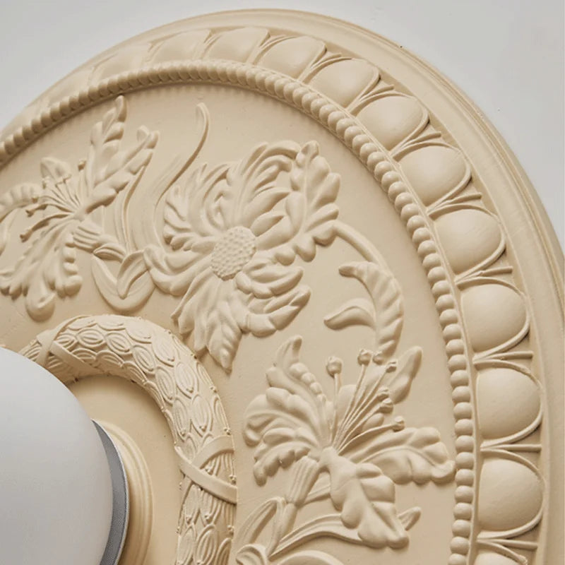 Close-up of beige LUXELY wall lamp showing detailed floral carvings, ideal for art deco interior lighting themes.