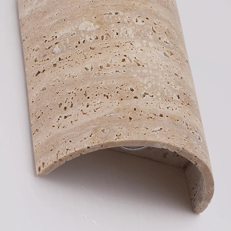 Close-up of curved travertine wall lamp IP65, highlighting textured stone surface and minimalist craftsmanship.
