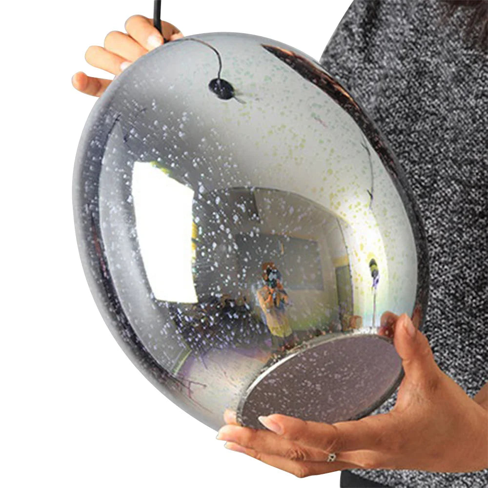 Person holding the modern 3D fireworks effect pendant light, showing the reflective glass sphere surface before installation.