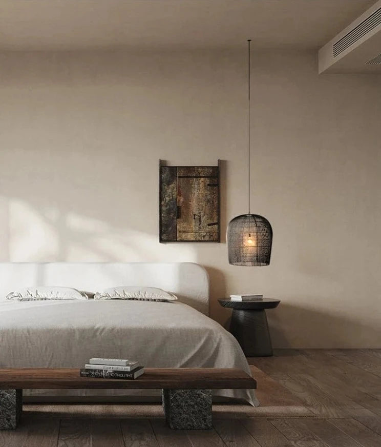 Black LUXELY rattan pendant lamp beside a minimalist bed, offering a rustic yet modern lighting solution.