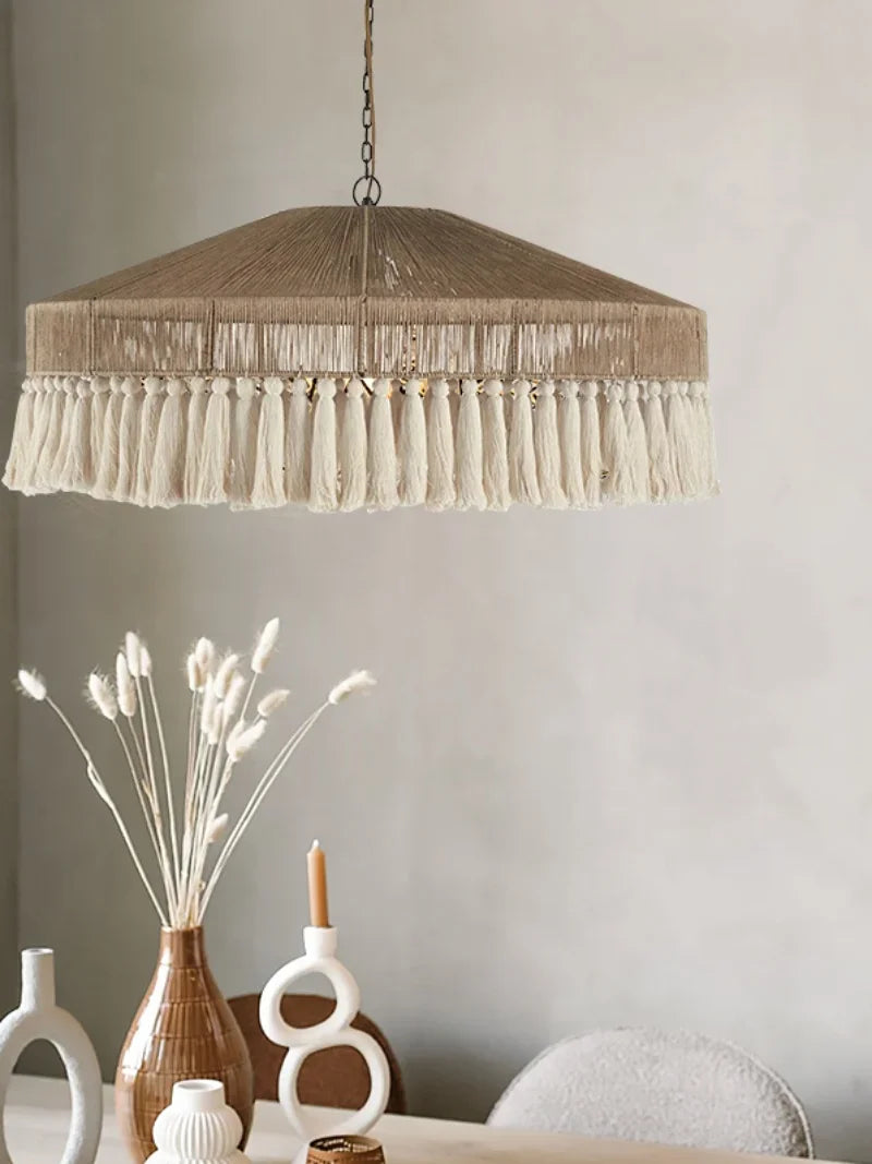 Wabi-Sabi Rattan Pendant Light over a minimalist dining table, showcasing its handmade design and natural cotton fringe.