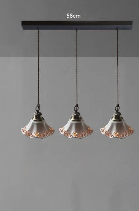 Three white ceramic pendant lights with cut-out edges on a 58cm mount, perfect for cozy kitchen or dining lighting.