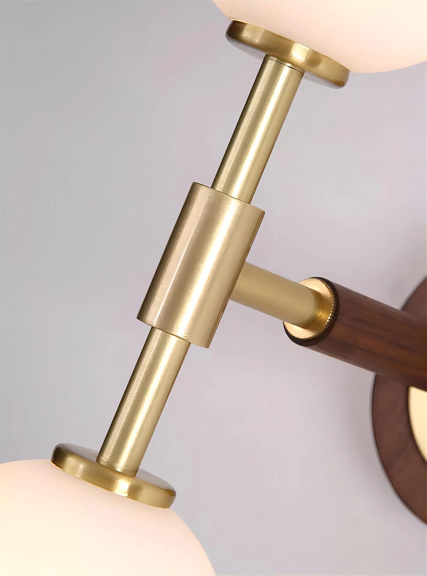 Detail of central brass connector on modern wall sconce, emphasizing sleek copper finish and durable build.