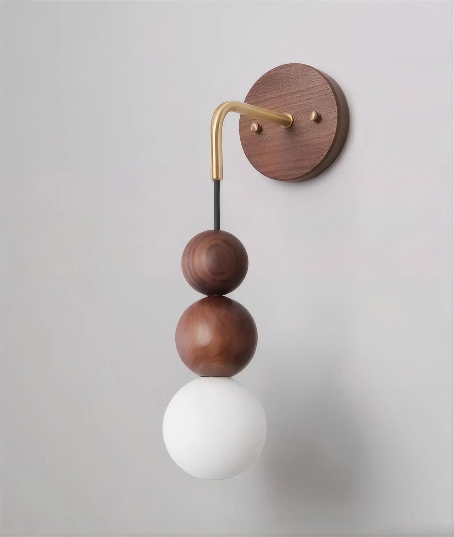 Side view of LUXELY walnut wood wall light with brass arm and matte glass globe, ideal for modern home interiors.
