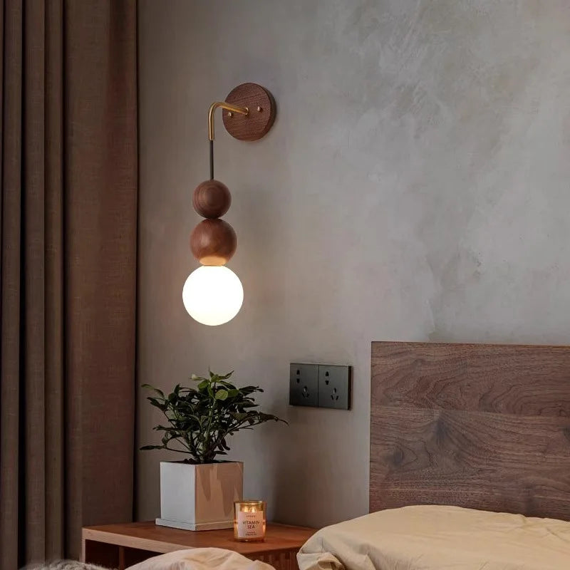 LUXELY walnut wood wall sconce with brass detail and soft glass light, mounted beside bed for cozy bedroom ambiance.