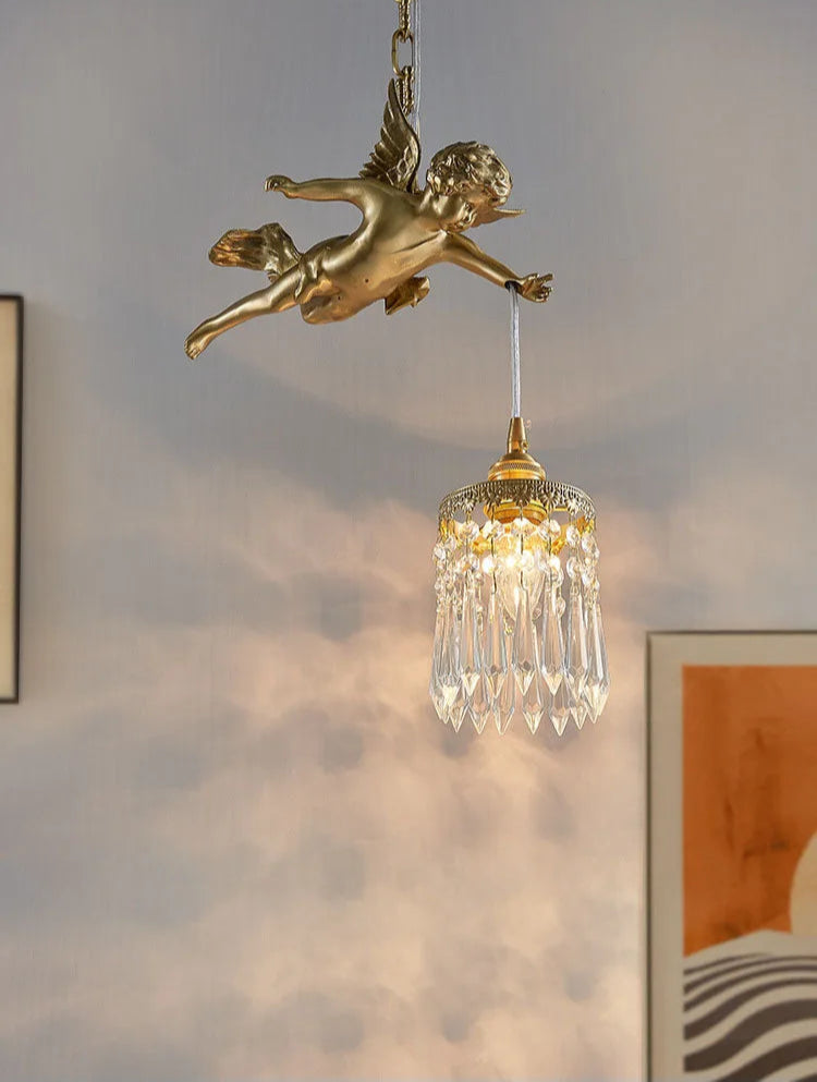 Copper angel chandelier with crystal pendant casting warm light on a minimalist wall, ideal for modern home decor.