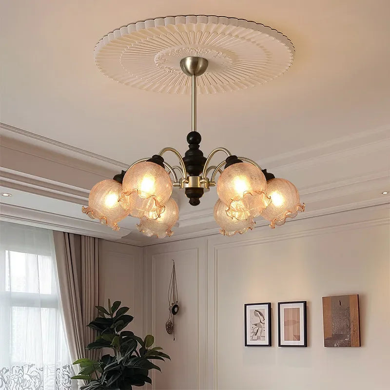 Modern crystal chandelier with LED lighting and floral glass shades, mounted on a decorative ceiling medallion in a classic interior.