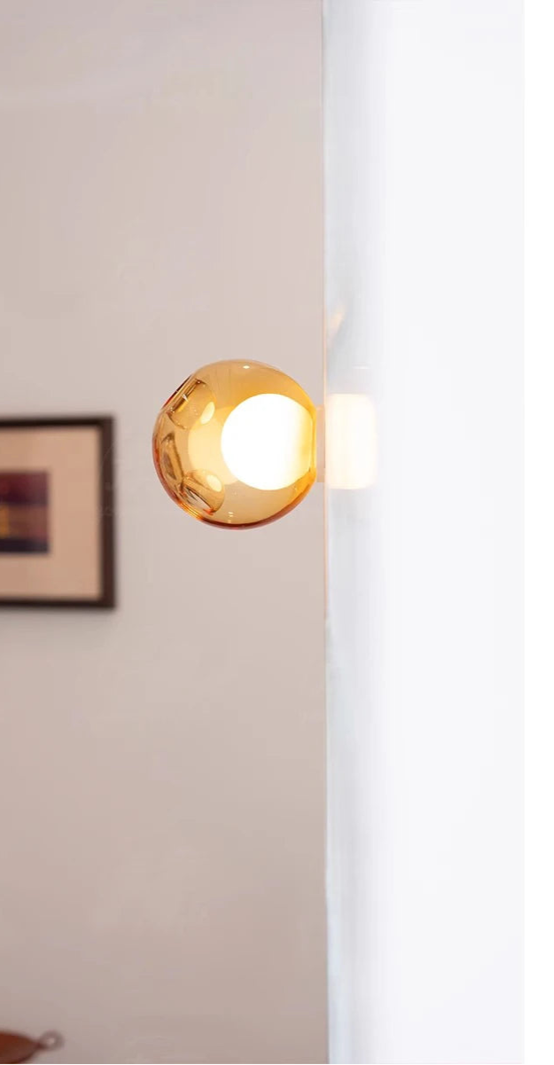 Amber glass ball LED wall light mounted on a white wall, offering a warm glow for modern bedroom or café ambiance.