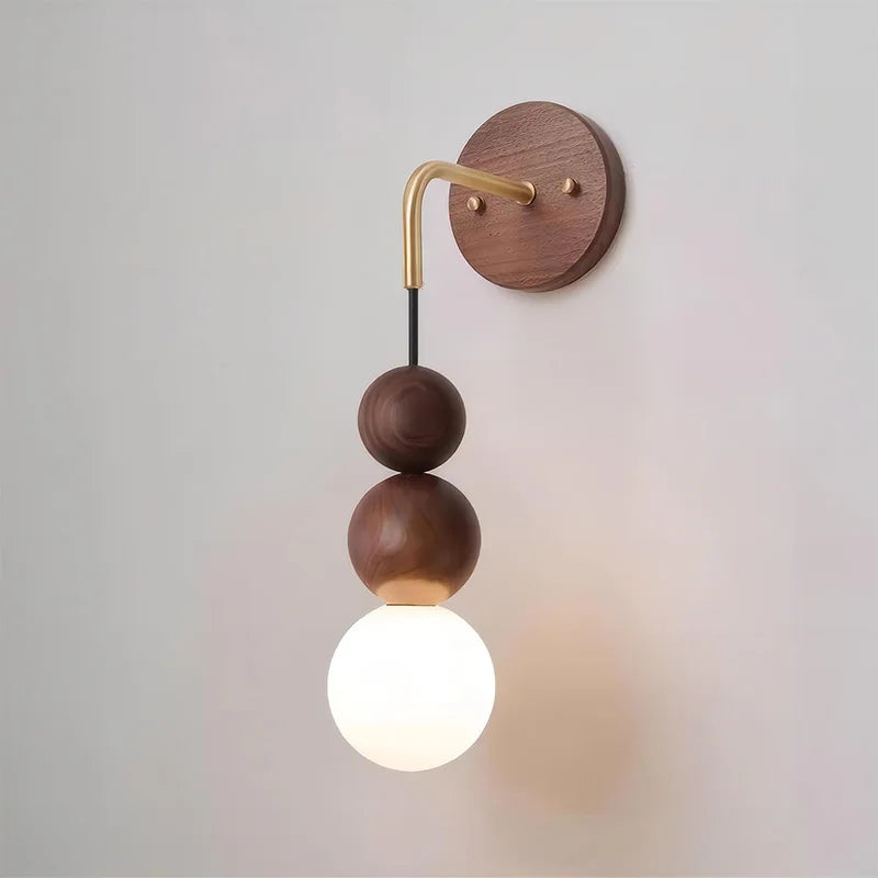 Close-up of LUXELY walnut wood wall sconce with brass arm and frosted glass globe, showcasing modern craftsmanship.