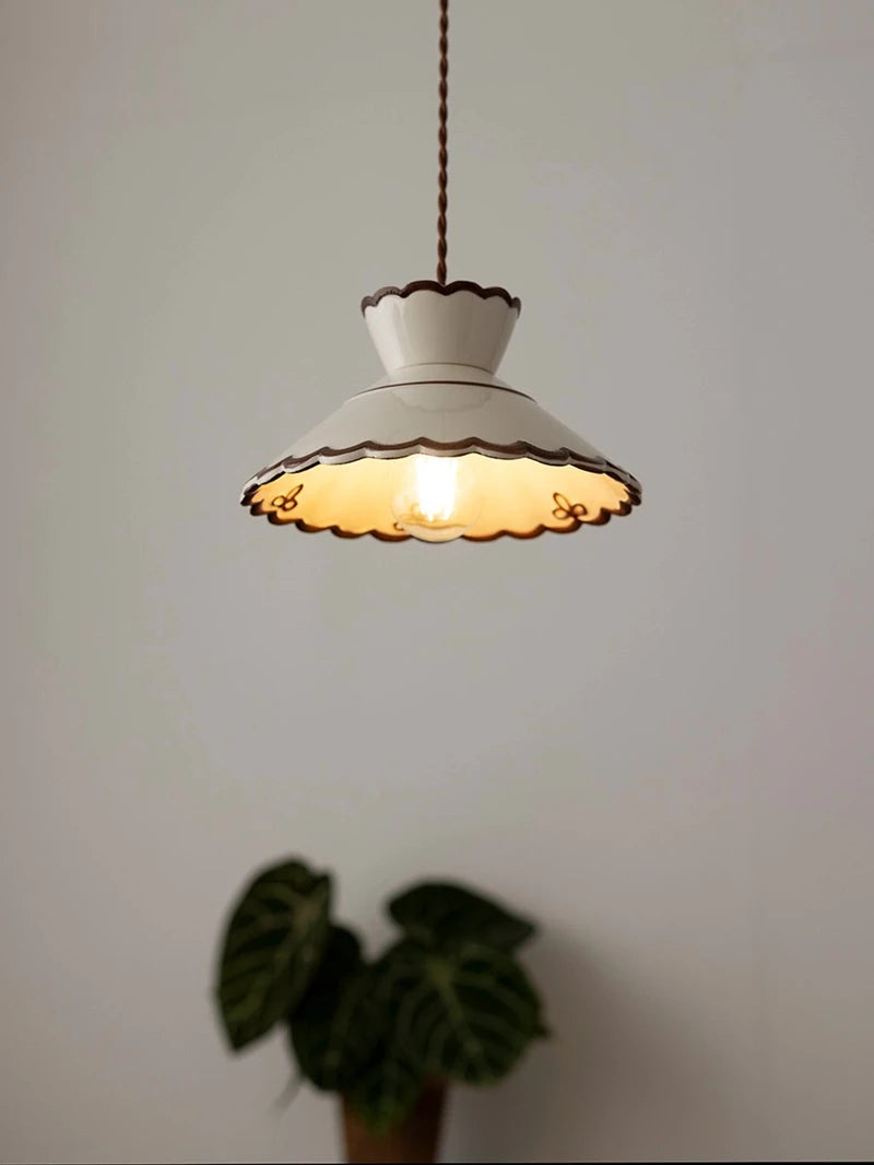 LED ceramic pendant lamp with scalloped edge and copper detailing, illuminating a cozy white room.