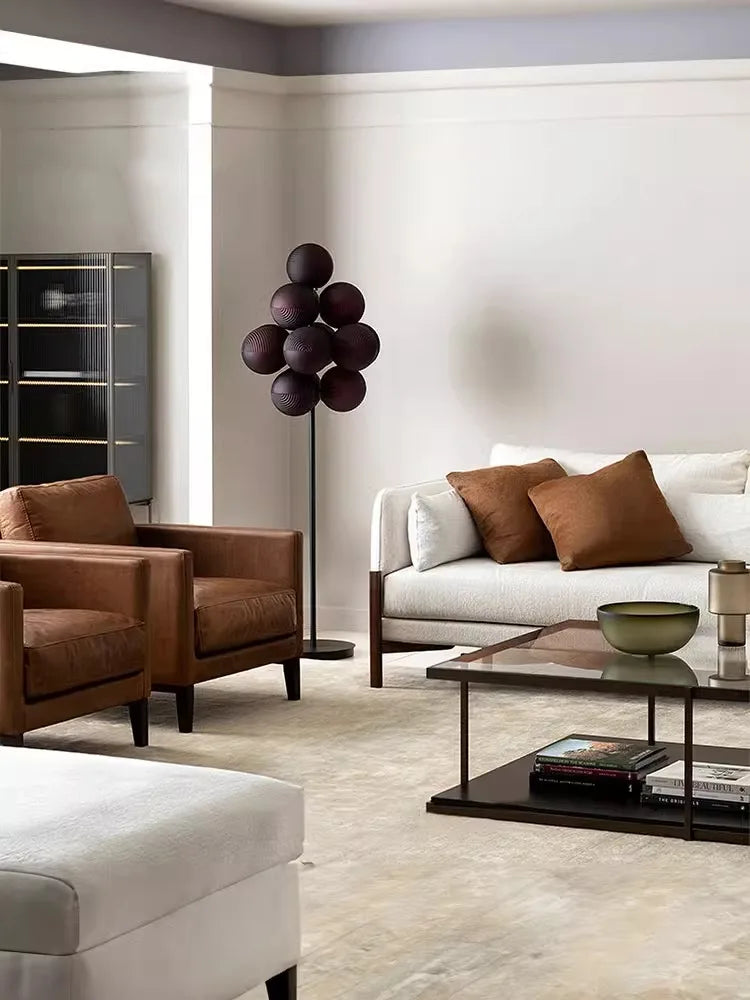 Floor-standing Grape LED Chandelier in purple glass beside a white sofa, enhancing the living room with a bold art deco accent.