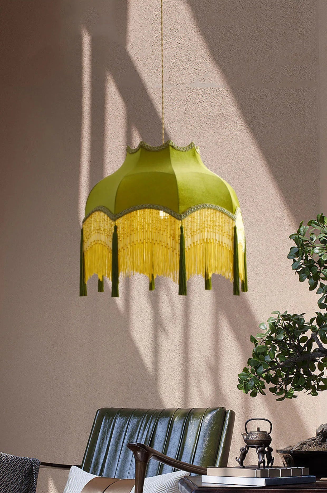 Green velvet pendant light with yellow fringe in a sunlit room, blending vintage charm with modern decor.