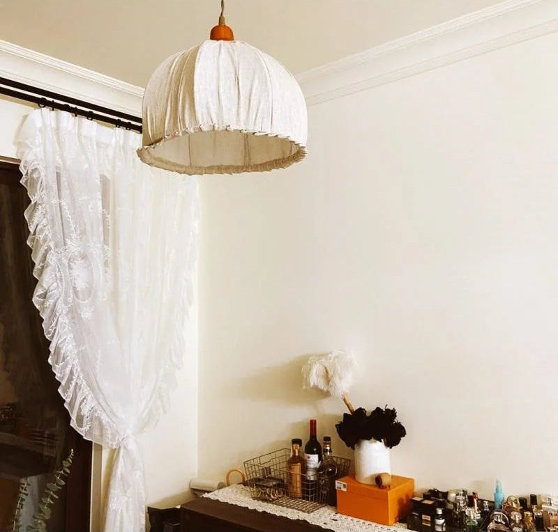 Pendant lamp hanging in cozy room with lace curtains and decor, enhancing the space with soft ambient lighting.