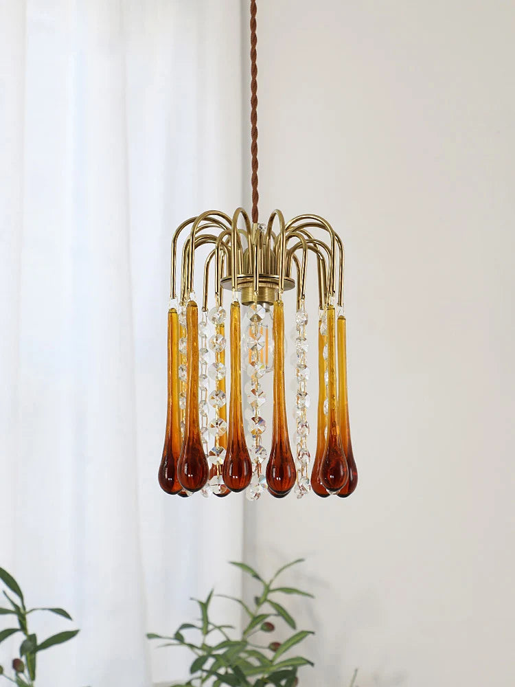 Close-up of vintage copper chandelier with amber and clear glass drops, showcasing intricate lighting fixture design.