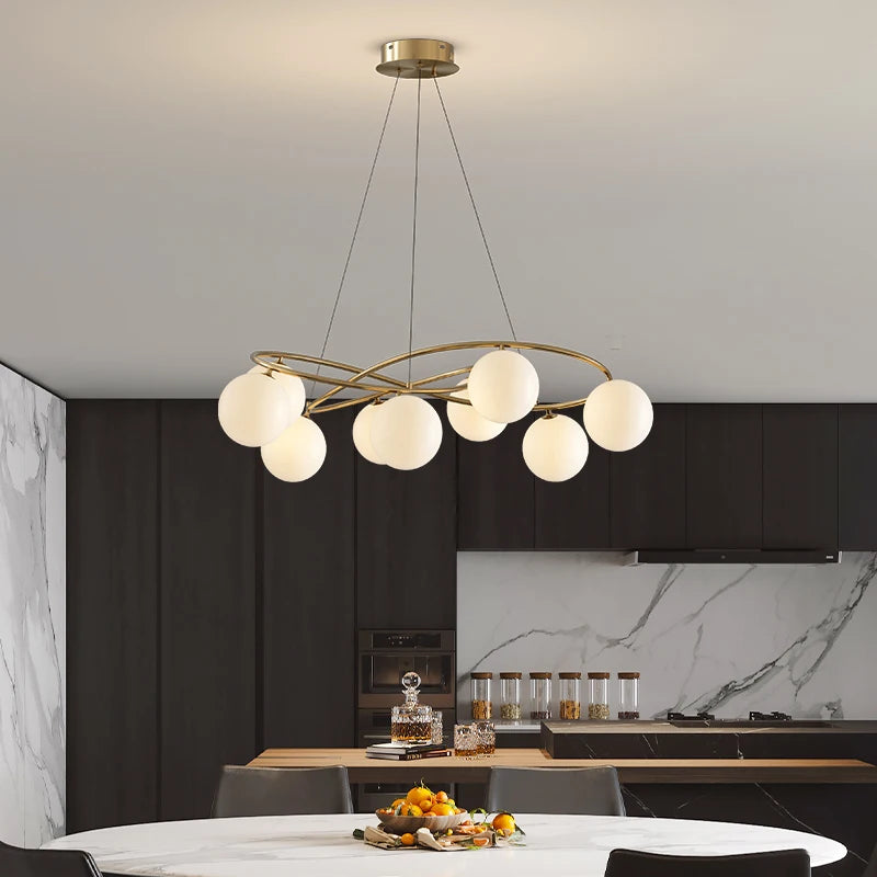 Modern Ceiling Light LED Chandelier in gold with globe bulbs, suspended over a round dining table in a sleek kitchen setting.