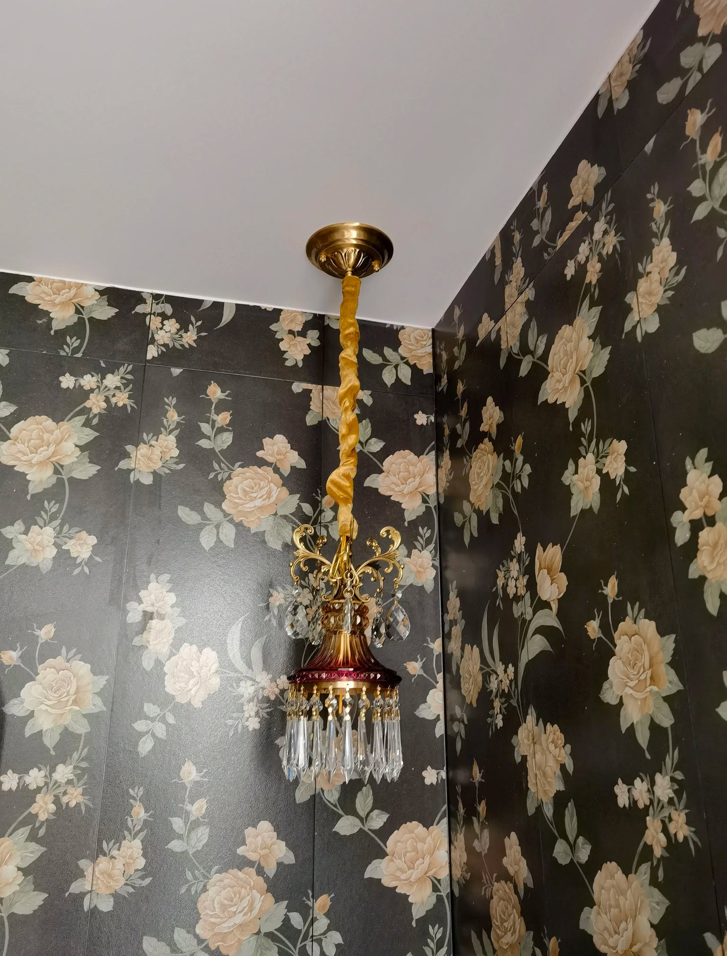 Vintage-style French crystal chandelier with twisted cord mount, luxury pendant light for floral wallpapered room.