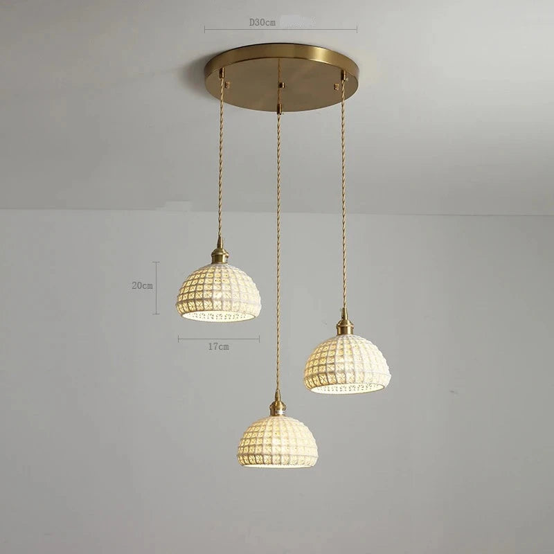 Triple white ceramic LED pendant lights by LUXELY mounted on a round brass ceiling plate, perfect for dining or kitchen lighting.