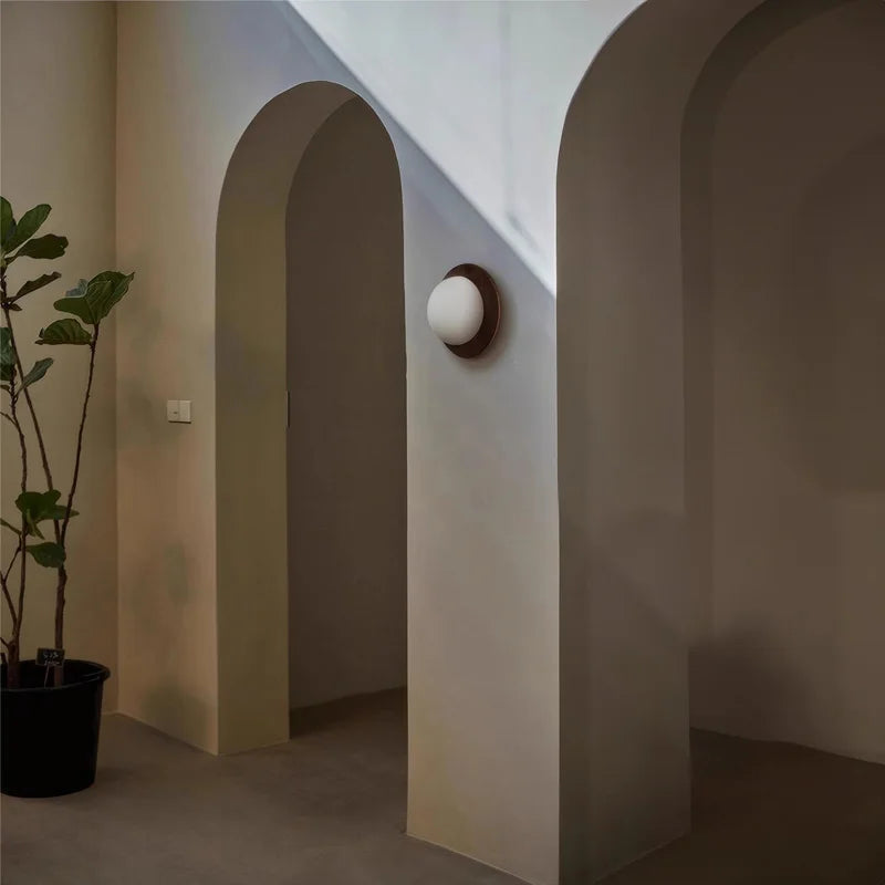 LUXELY walnut wood wall sconce mounted in arched hallway, blending wabi-sabi style with soft ambient lighting.