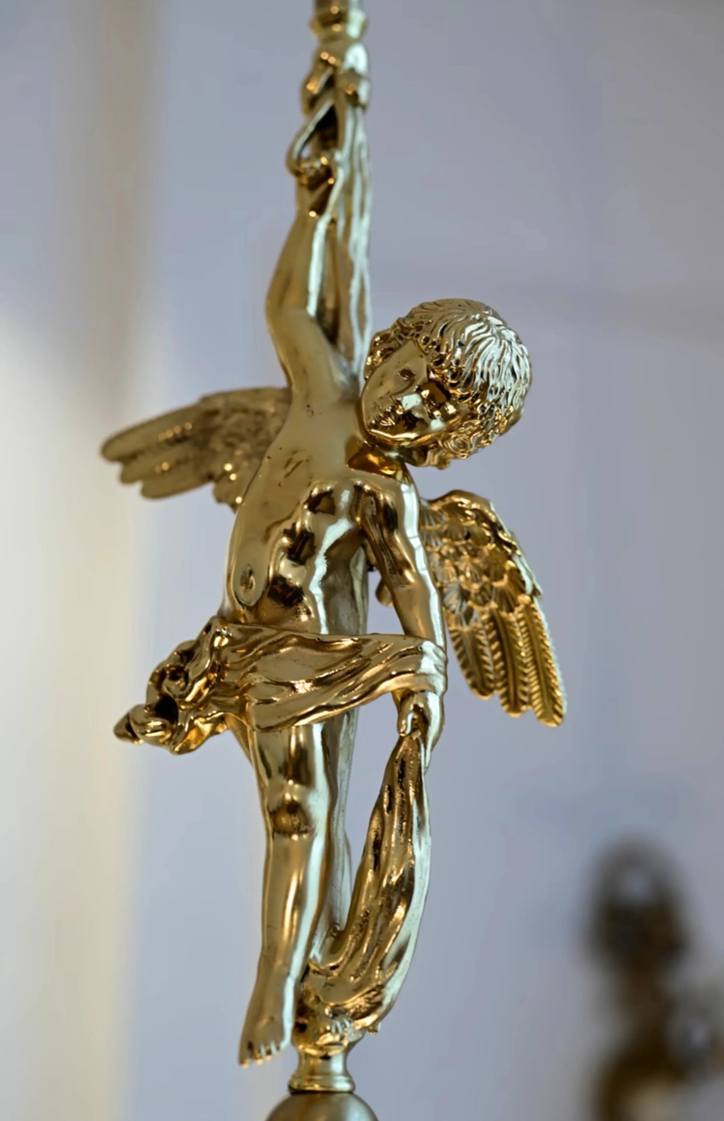 Close-up of gold copper angel figure on modern pendant light, showcasing intricate detailing for luxury home lighting fixtures.