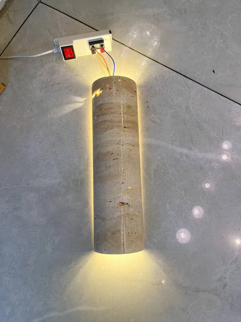IP65 Travertine wall lamp tested on floor with LED light on, highlighting its durable stone body and soft ambient glow.