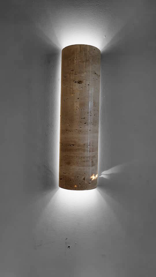 Mounted IP65 Travertine wall lamp emitting soft white LED light upward and downward, suitable for hallway or bathroom lighting.