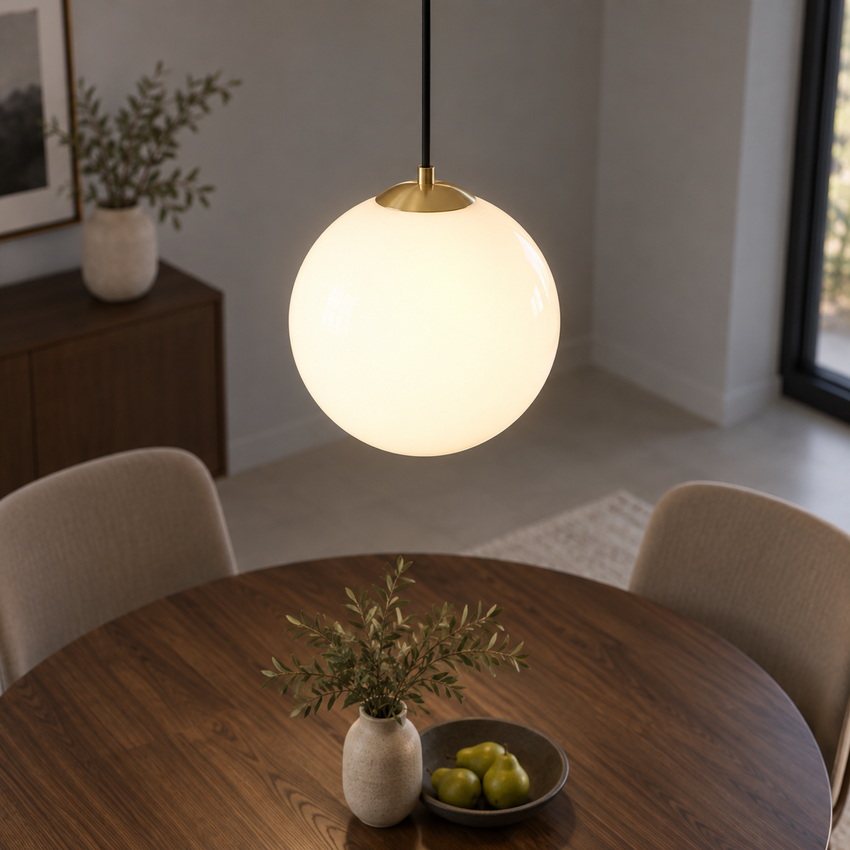 White glass globe pendant with adjustable cord, elevated view of gold fitting over a dining table