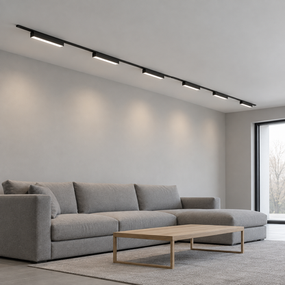 Black ultra-thin surface track with linear LED modules installed above a grey living room