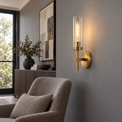 Gold clear glass cylinder wall light installed beside a gray reading chair