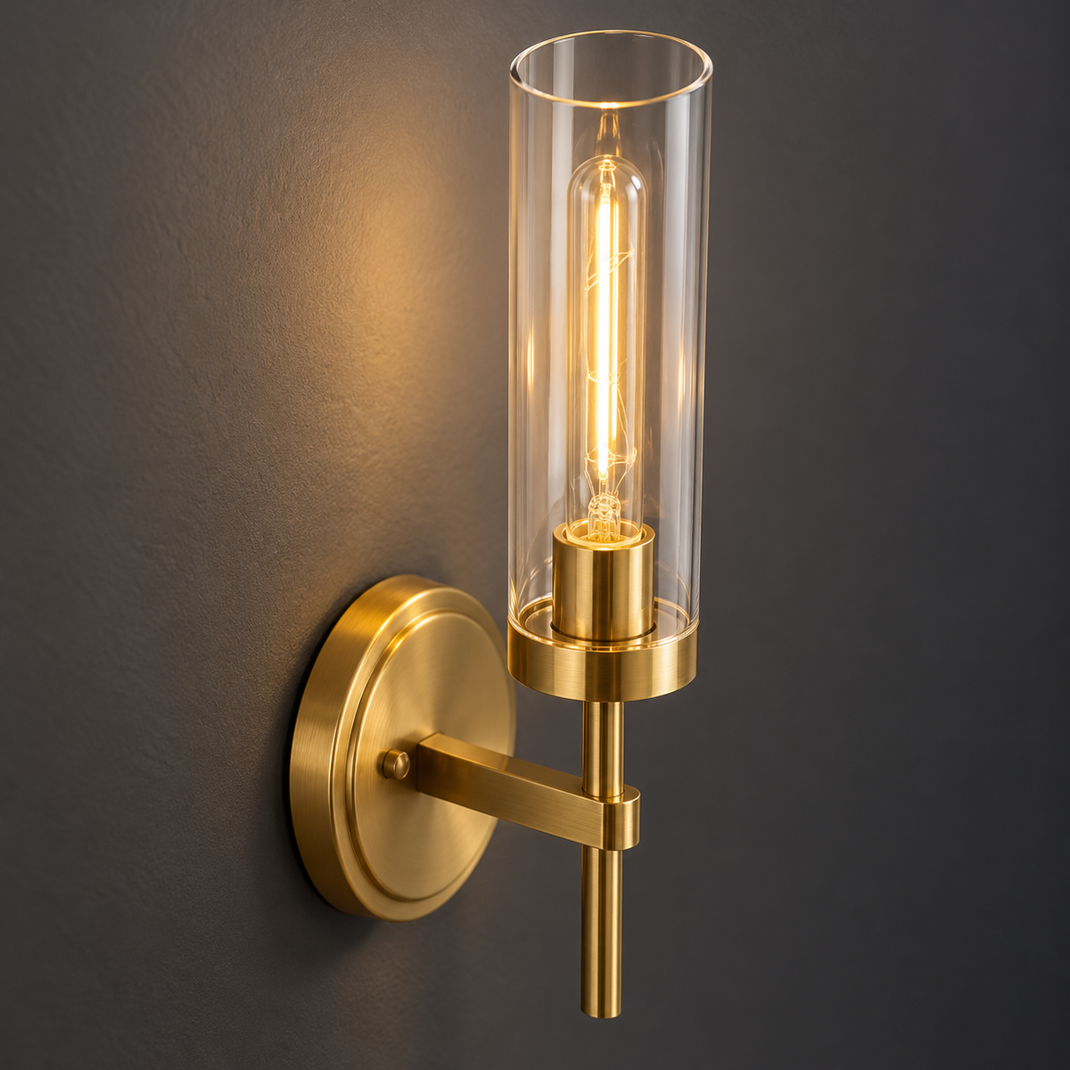 Close-up of the clear glass shade and gold socket of the cylinder wall light