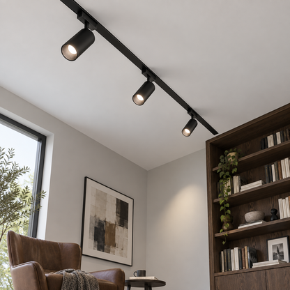 Low-angle room view of three black magnetic spotlights secured in a ceiling rail