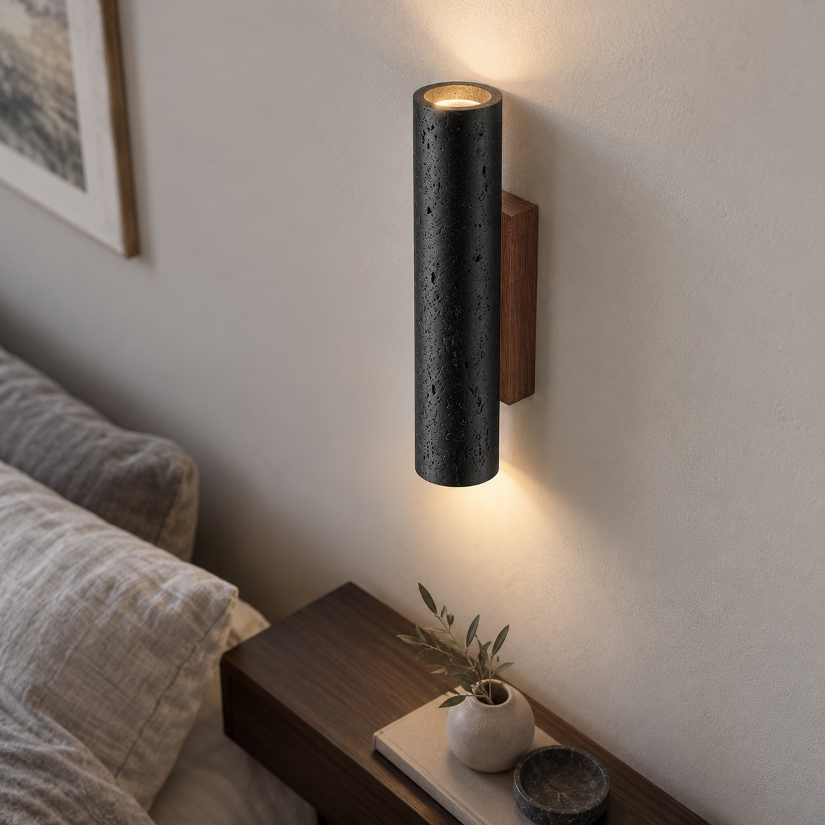Above-angle photograph of the black cylindrical travertine wall light with light spilling up and down
