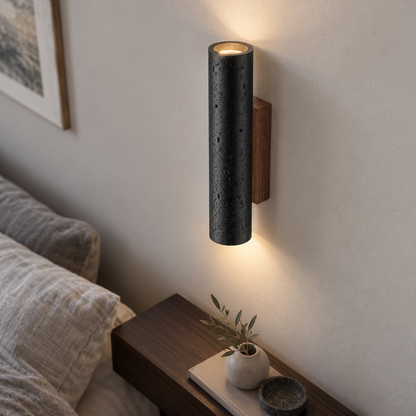 Above-angle photograph of the black cylindrical travertine wall light with light spilling up and down