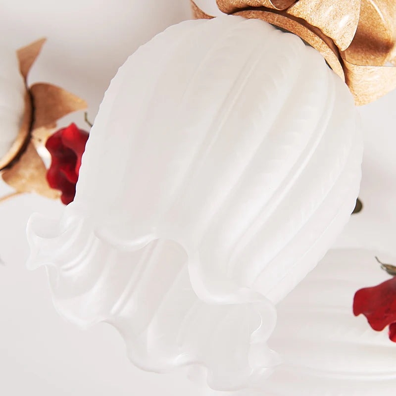 Close-up of frosted glass flower-shaped LED light on romantic rose bedroom pendant chandelier for vintage-inspired interiors.