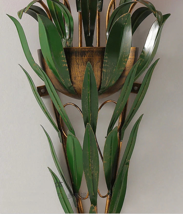 Close-up of rustic green leaf metalwork on French country wall light, showcasing detailed craftsmanship and vintage finish.
