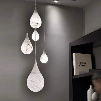 Teardrop marble LED pendant lights in a cozy corner. Marble LED pendant light – modern ceiling lamp dimmable for soft ambient lighting.