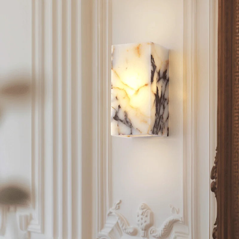 Elegant black marble wall sconce mounted on ornate white wall, ideal for luxury bedroom or bathroom decor.