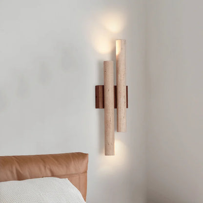 Wall-mounted travertine stone bedroom wall lamp with warm LED strip lighting, shown beside a leather headboard for cozy room ambiance.