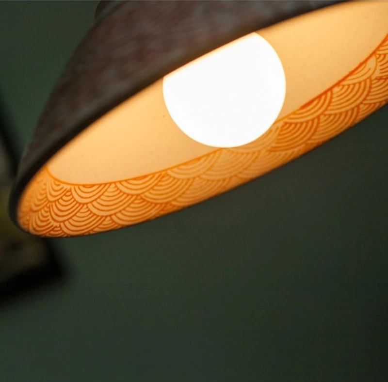 Interior view of orange wave ceramic pendant lamp with LED bulb, highlighting hand-painted design and glossy finish.
