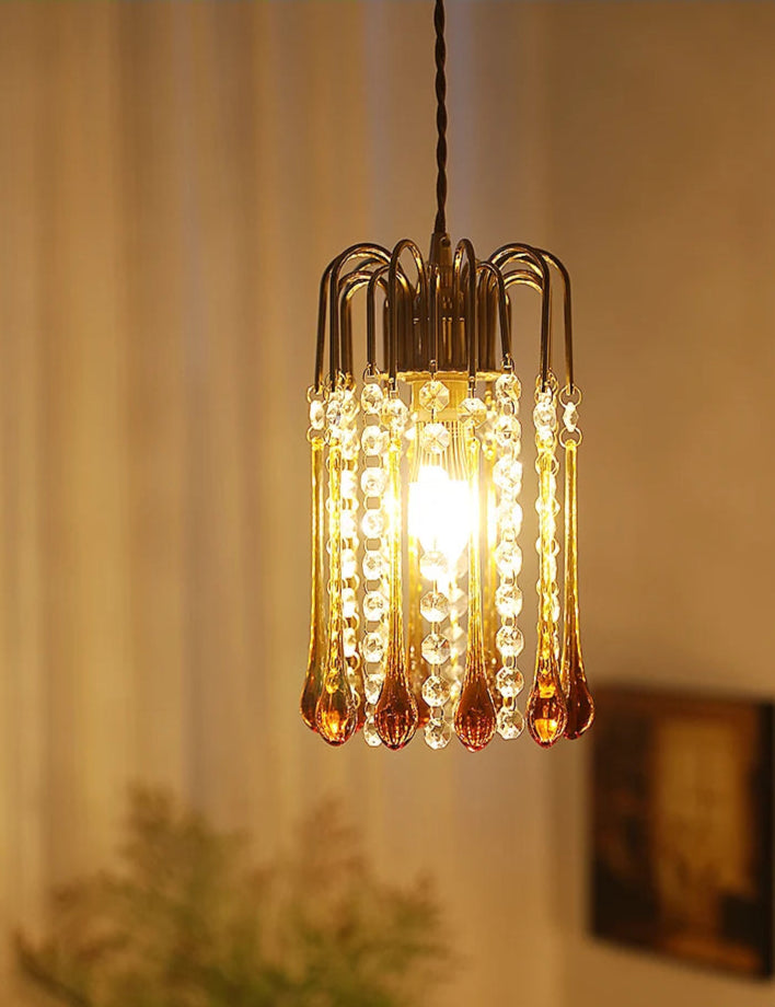 Warmly lit vintage chandelier with copper and glass water drop design, perfect for cozy interior lighting.