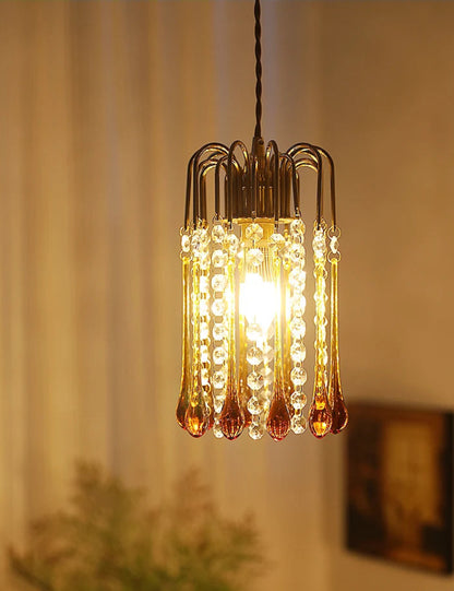 Warmly lit vintage chandelier with copper and glass water drop design, perfect for cozy interior lighting.