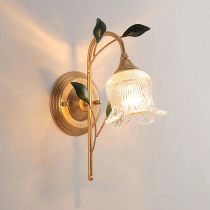 French Wall Sconce Light with golden branch and green leaf design, featuring a fluted glass flower shade and LED bulb for bedroom lighting.