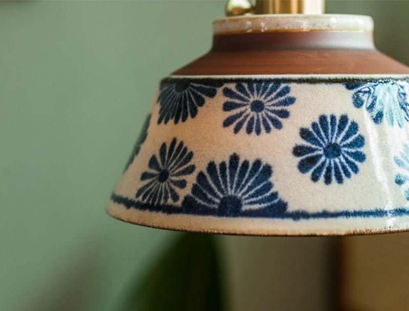 Close-up of floral ceramic pendant lamp with LED bulb, featuring hand-painted blue flowers for vintage lighting charm.