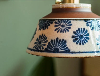 Close-up of floral ceramic pendant lamp with LED bulb, featuring hand-painted blue flowers for vintage lighting charm.