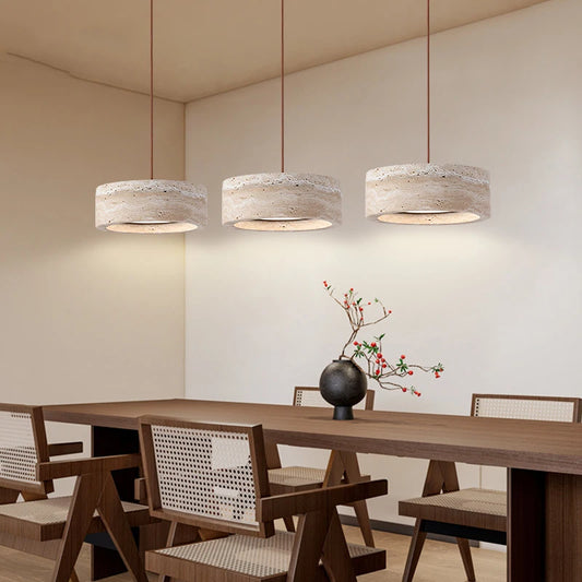 Travertine Stone LED Pendant Light – Modern Fixture shown in a dining room with three cylindrical lights above a wooden table and chairs.
