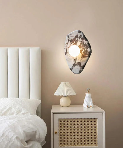 G9 Stone Wall Light with glass globe sconce above a nightstand, offering soft lighting for a modern bedroom setup.